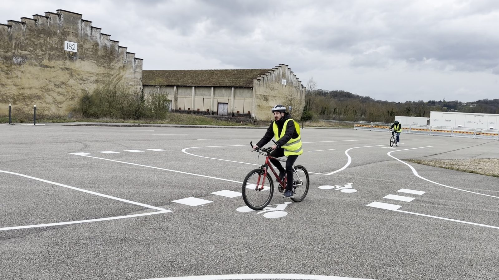 A cyclist wearing a helmet rides through the test intersection at Transpolis during a helmet-detection scenario