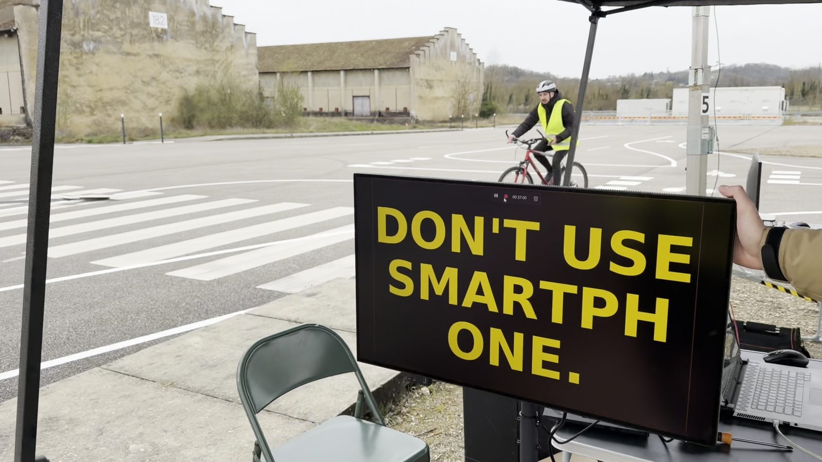 A variable message sign displays the warning “Don’t use smartphone” as a cyclist passes during the pilot