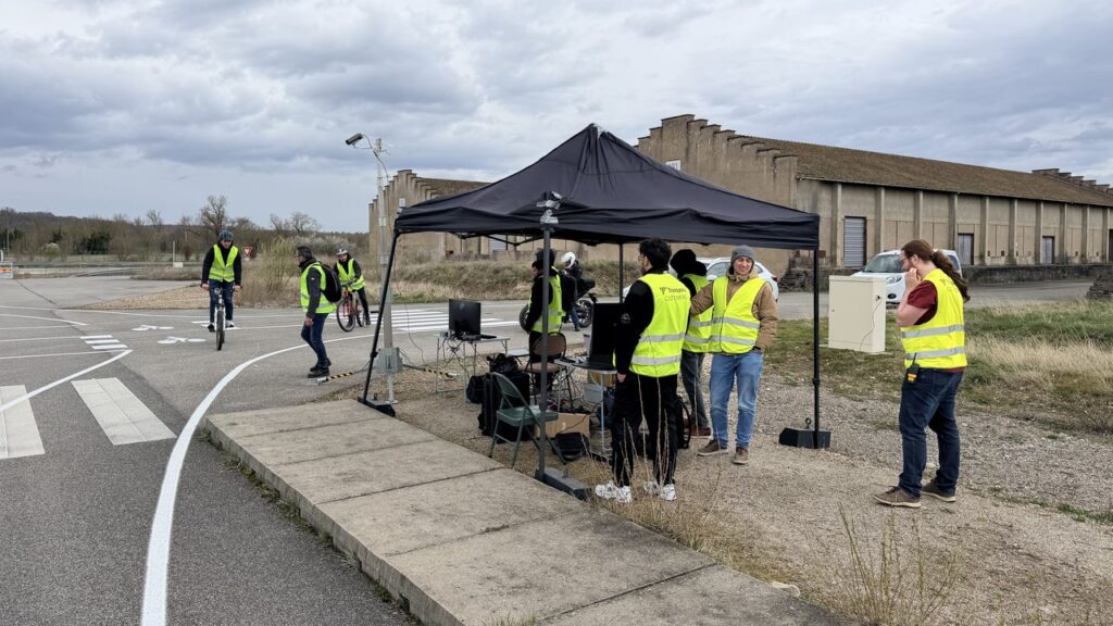 The iDriving pilot set-up at the Transpolis test track: a control tent with monitors next to a test intersection with cycle lanes and a zebra crossing